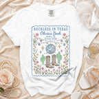 White t-shirt with "Reckless in Texas Olivia's Bach" graphic, cacti, disco ball.