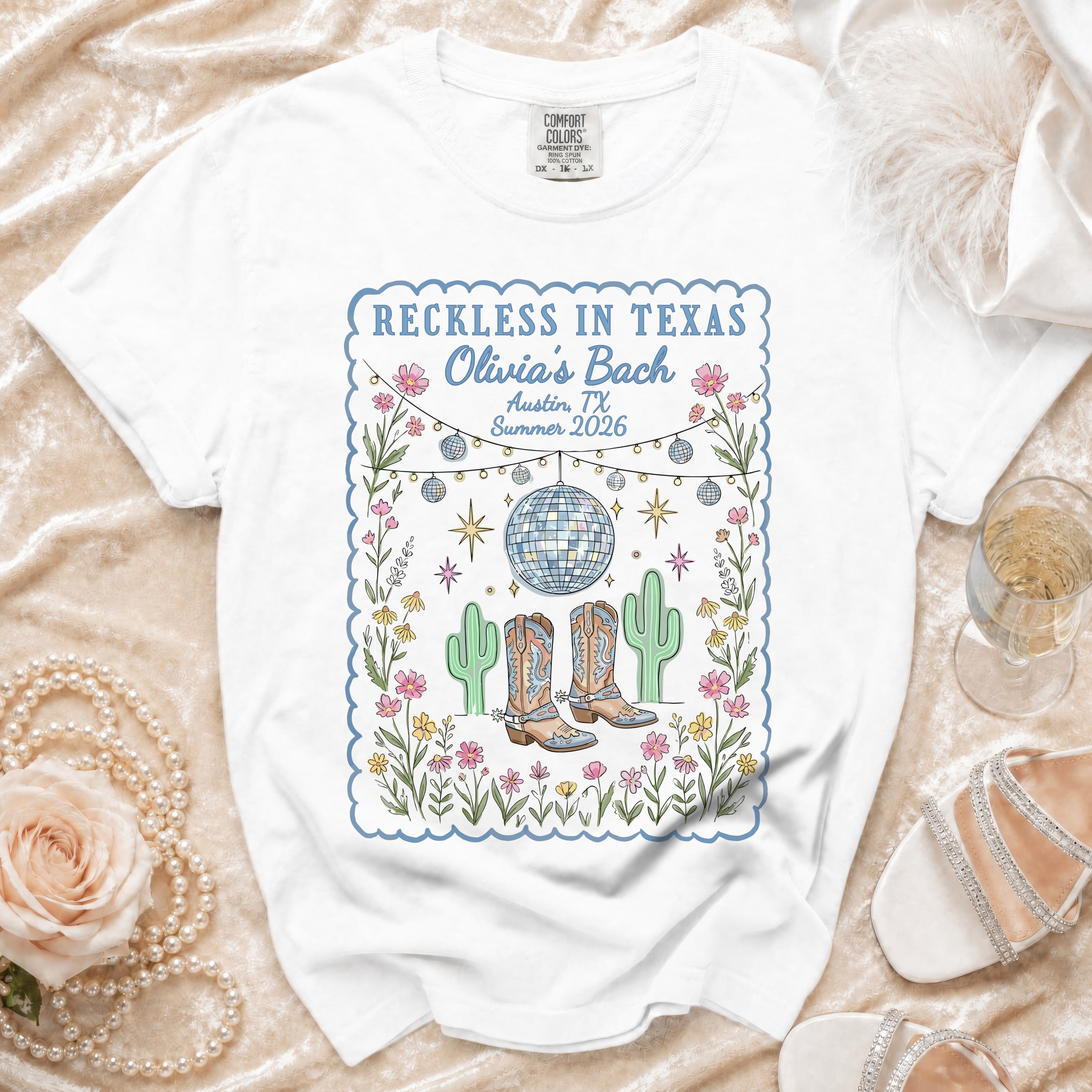 White t-shirt with "Reckless in Texas Olivia's Bach" graphic, cacti, disco ball.