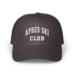 A dark grey baseball cap with white embroidered text reading APRES SKI CLUB on the front.