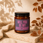 Candle with text "Will you be my bridesmaid?" on a stone block with autumn leaves.