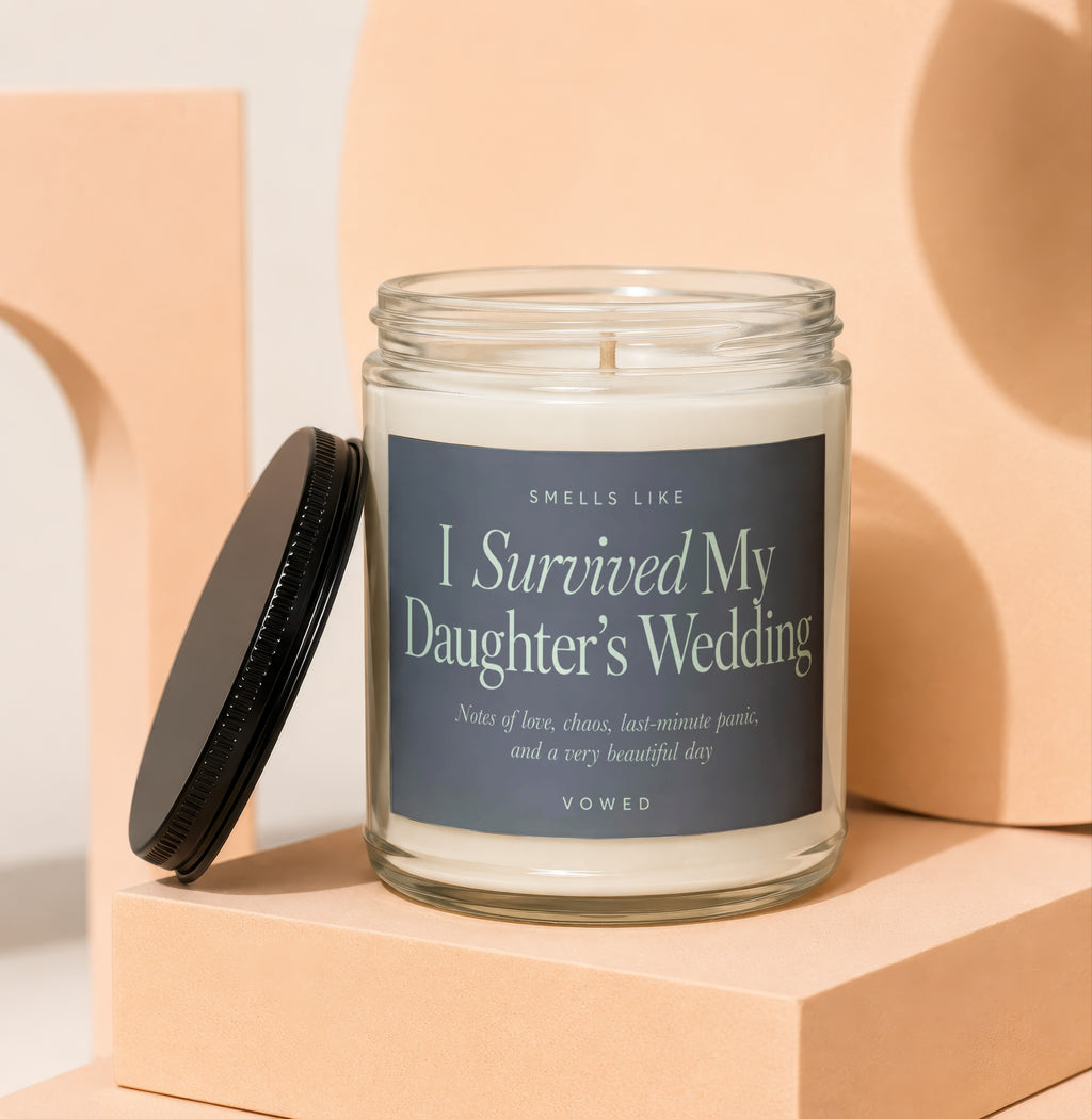 Glass candle with dark label reading "I Survived My Daughter's Wedding."