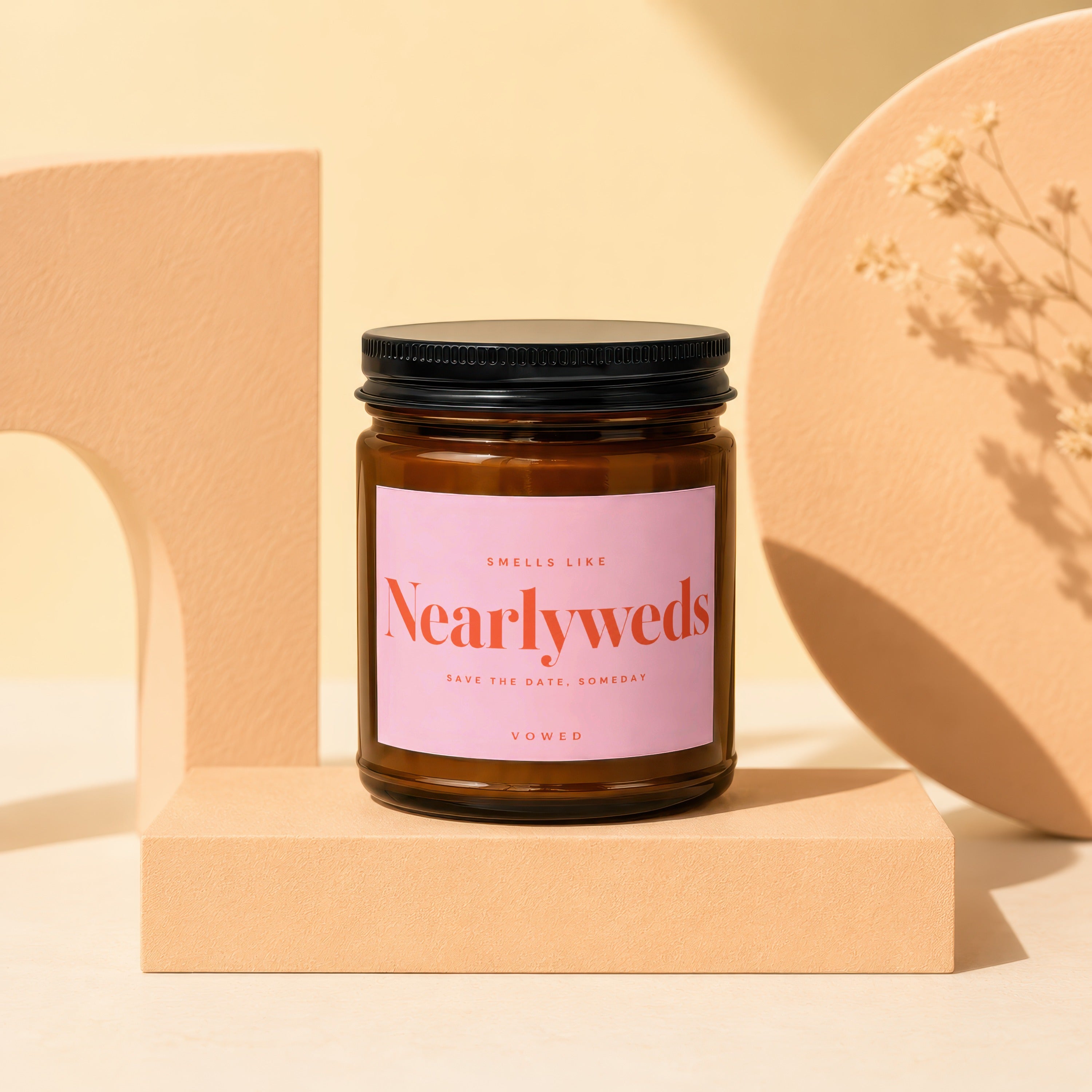Amber jar candle with pink label reading "Smells Like Nearlyweds Save the Date, Someday Vowed".