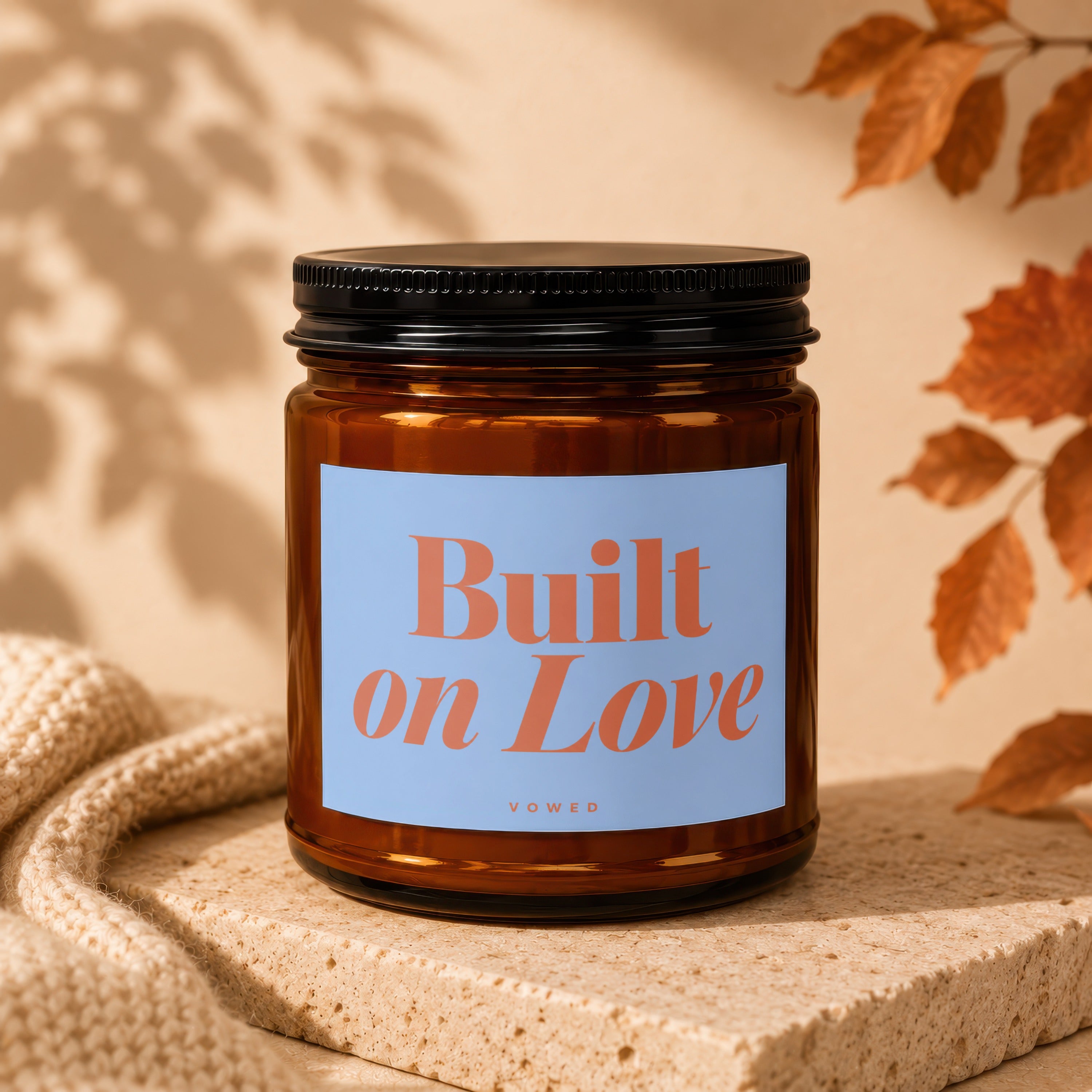 Amber glass candle with a light blue label that says "Built on Love" above "vowed".