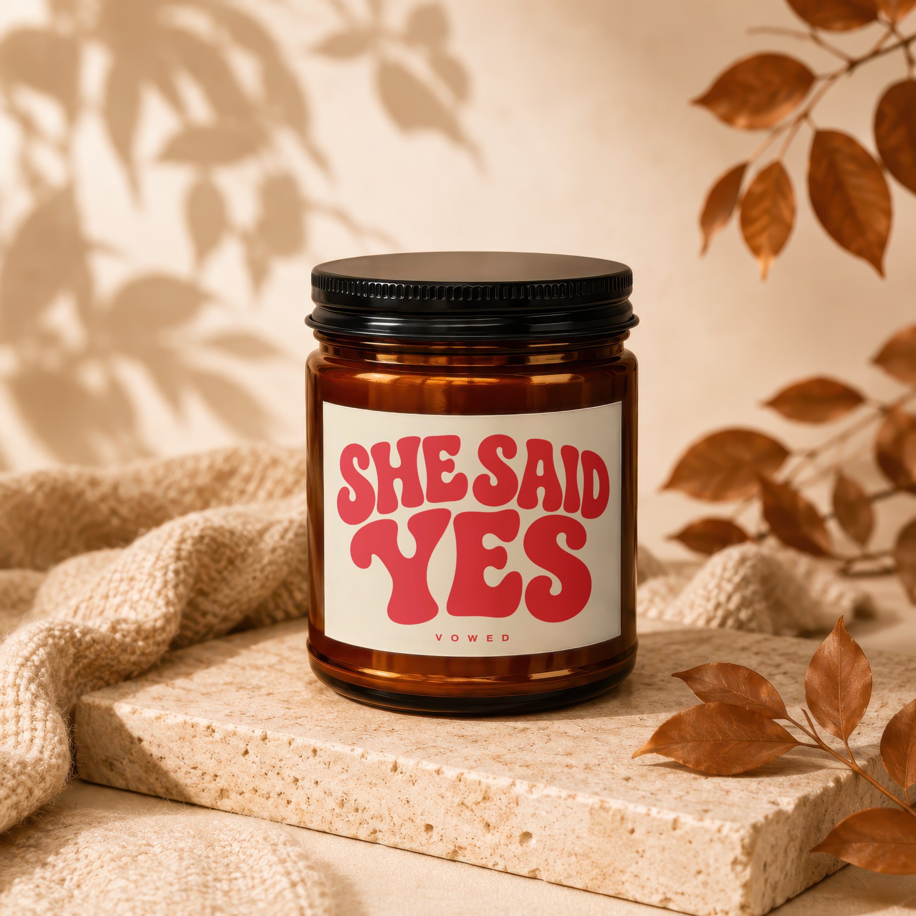 Amber candle with "SHE SAID YES" in pink retro font on label.