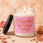 Burning candle in glass jar with pink label saying "Married the whole vibe vowed".