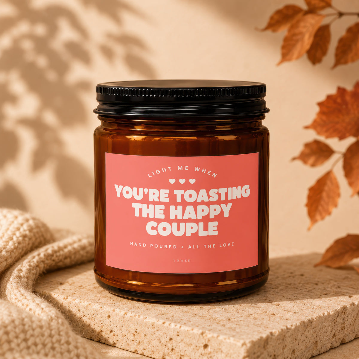 Amber glass candle with pink label reading "You're Toasting the Happy Couple."