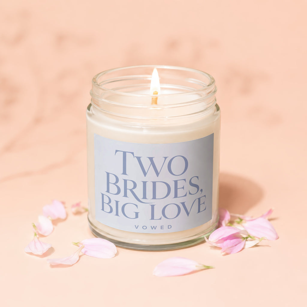 Candle with label "TWO BRIDES, BIG LOVE VOWED" surrounded by pink flower petals.