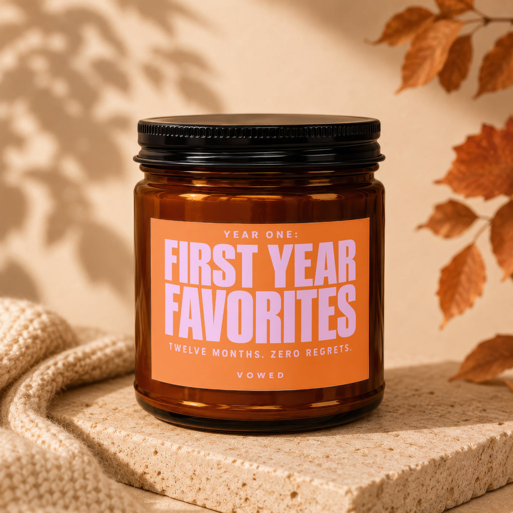 Amber jar candle with orange label reading "YEAR ONE: FIRST YEAR FAVORITES", "TWELVE MONTHS. ZERO REGRETS.", "VOWED".