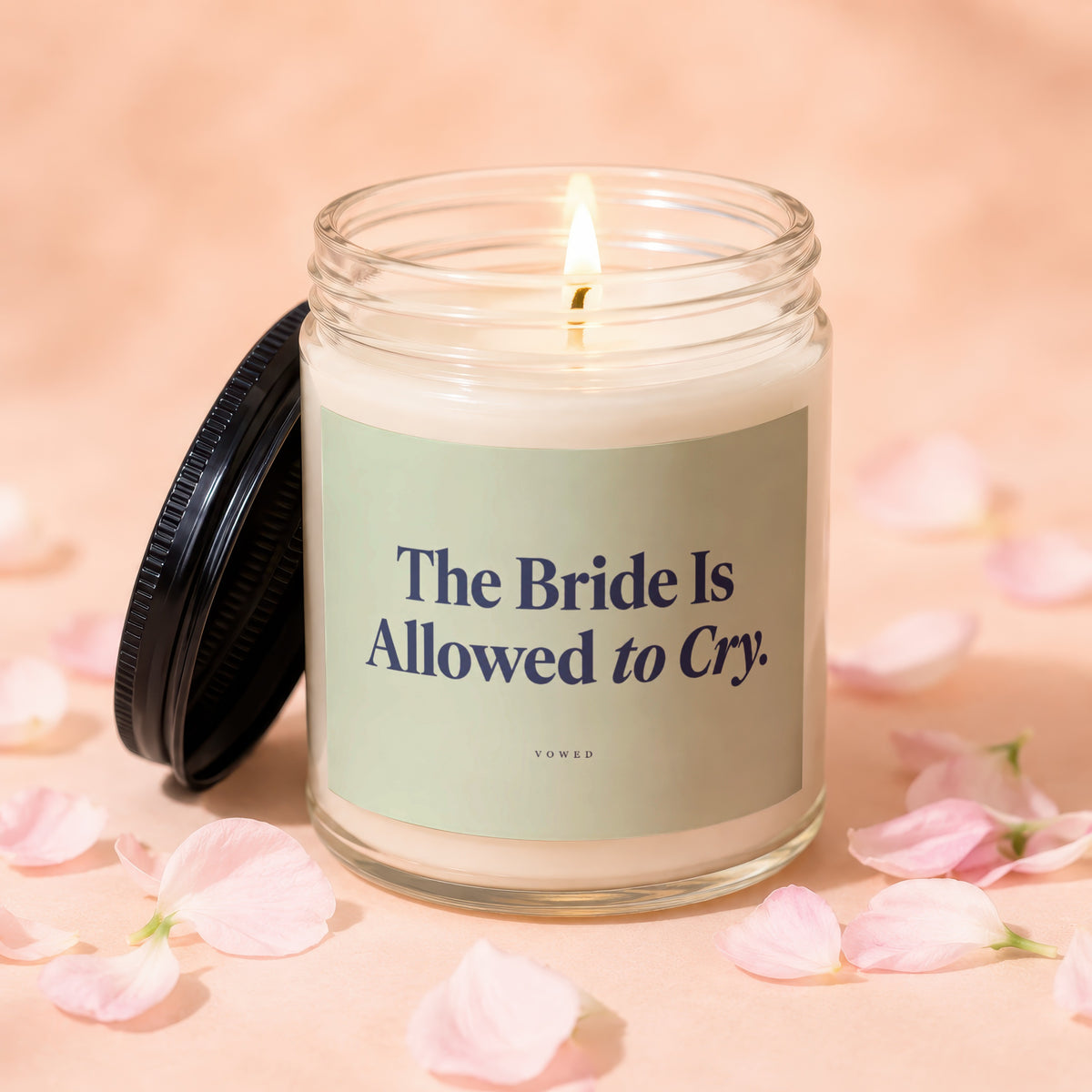 Lit candle in glass jar with lid off, inscribed "The Bride Is Allowed to Cry."