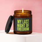 Amber candle with lit flame and black lid, reads "My Last Night of Freedom."