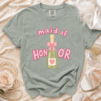 Maid of Honor shirt with champagne bottle graphic and pink lettering.