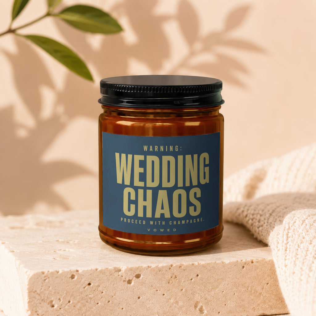 Amber jar candle with dark blue label that reads: WARNING: WEDDING CHAOS. PROCEED WITH CHAMPAGNE. VOWED.
