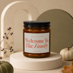 Amber glass candle with black lid, "Welcome To The Family" text.