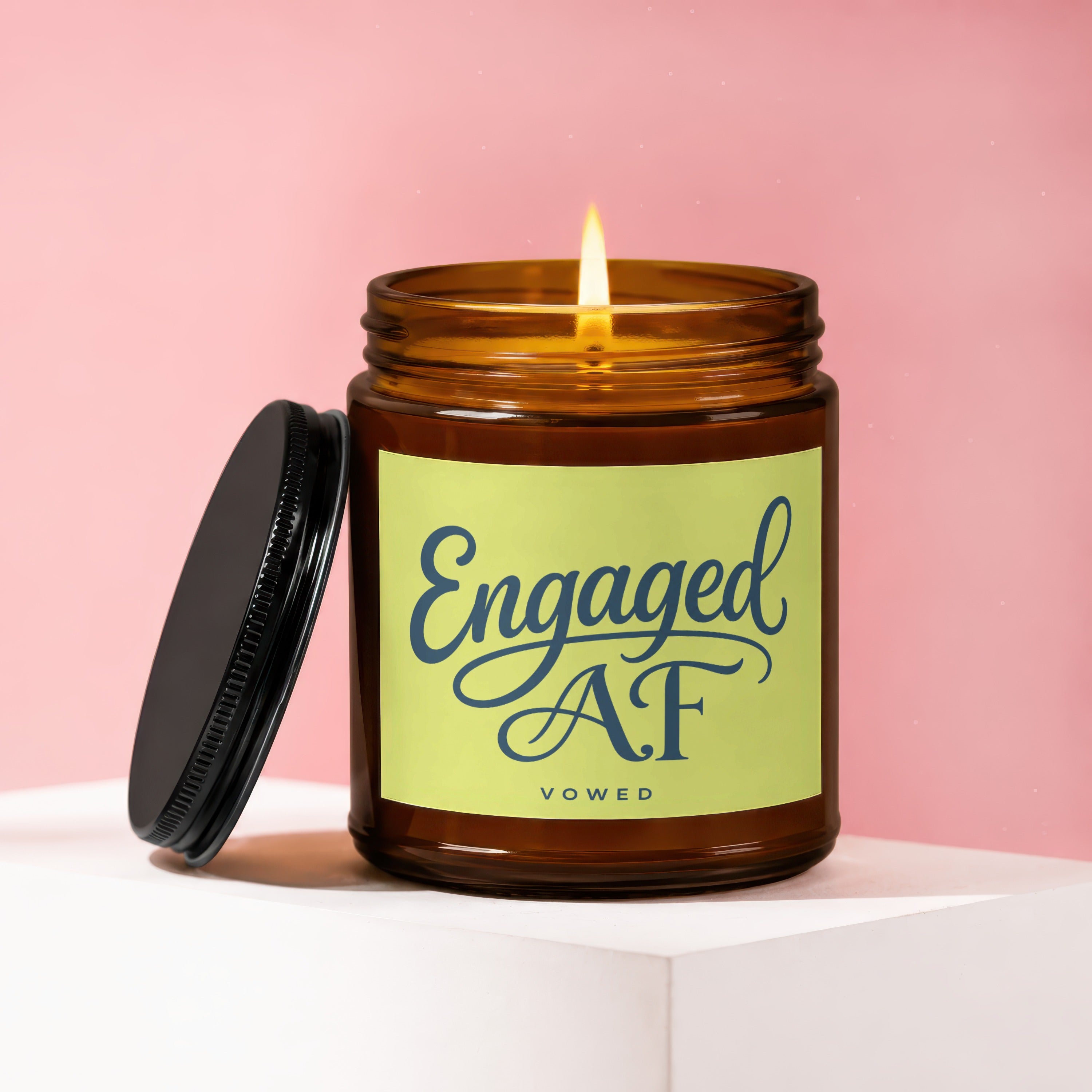 Amber jar candle with lit wick and "Engaged AF VOWED" text on a light green label.