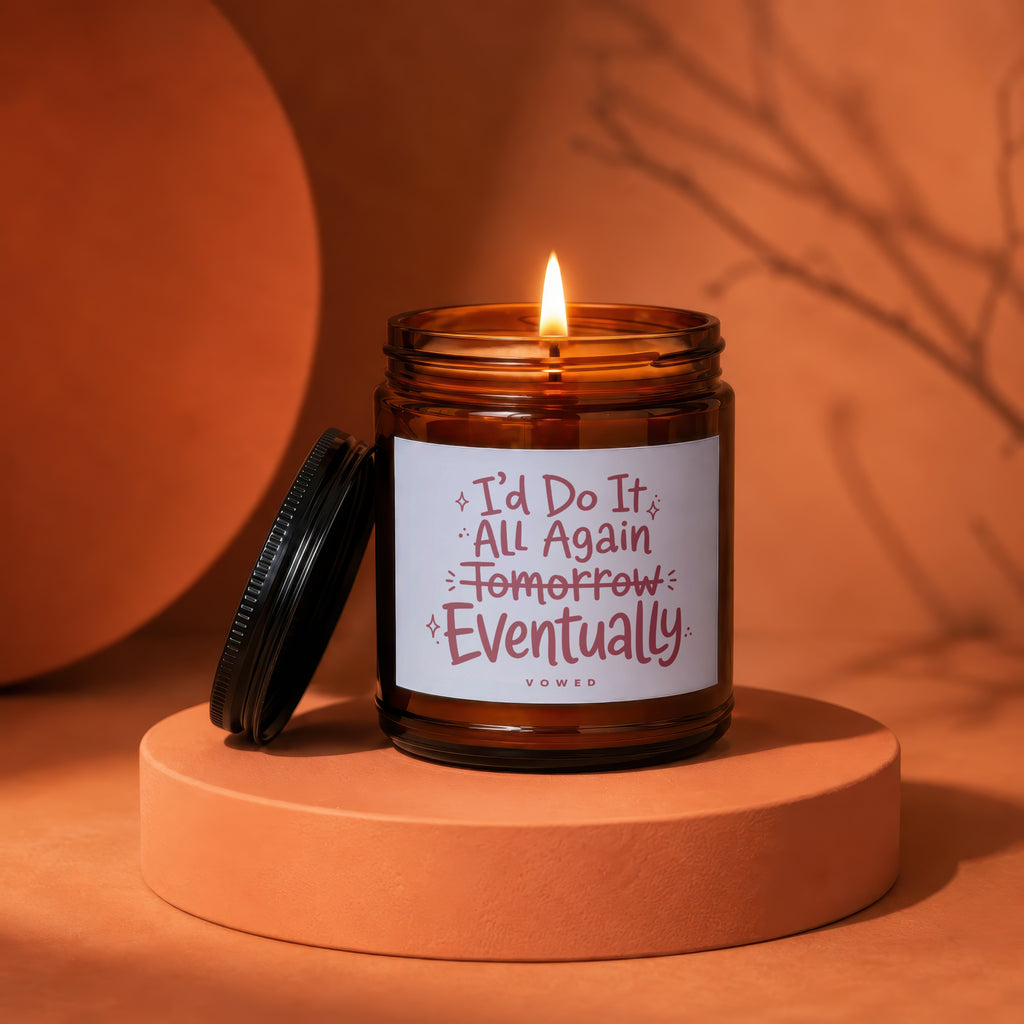 Amber jar candle with lit flame, reads "I'd Do It All Again Tomorrow Eventually".