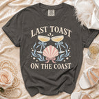 T-shirt with "Last Toast On The Coast" text and seaside graphics.