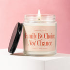 Glass jar candle with lit wick and black lid, text reads "Family By Choice, Not Chance".