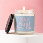 Lit candle in a jar with black lid, featuring "She Said Yes Too" text.