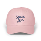 A light pink baseball cap features embroidered blue text reading Snow in Love on the front.