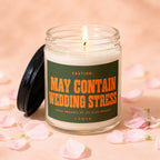 Candle with label reading "CAUTION: MAY CONTAIN WEDDING STRESS" surrounded by pink petals.