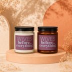 Two "Wives before everything" candles, one clear, one amber, with dried flowers.