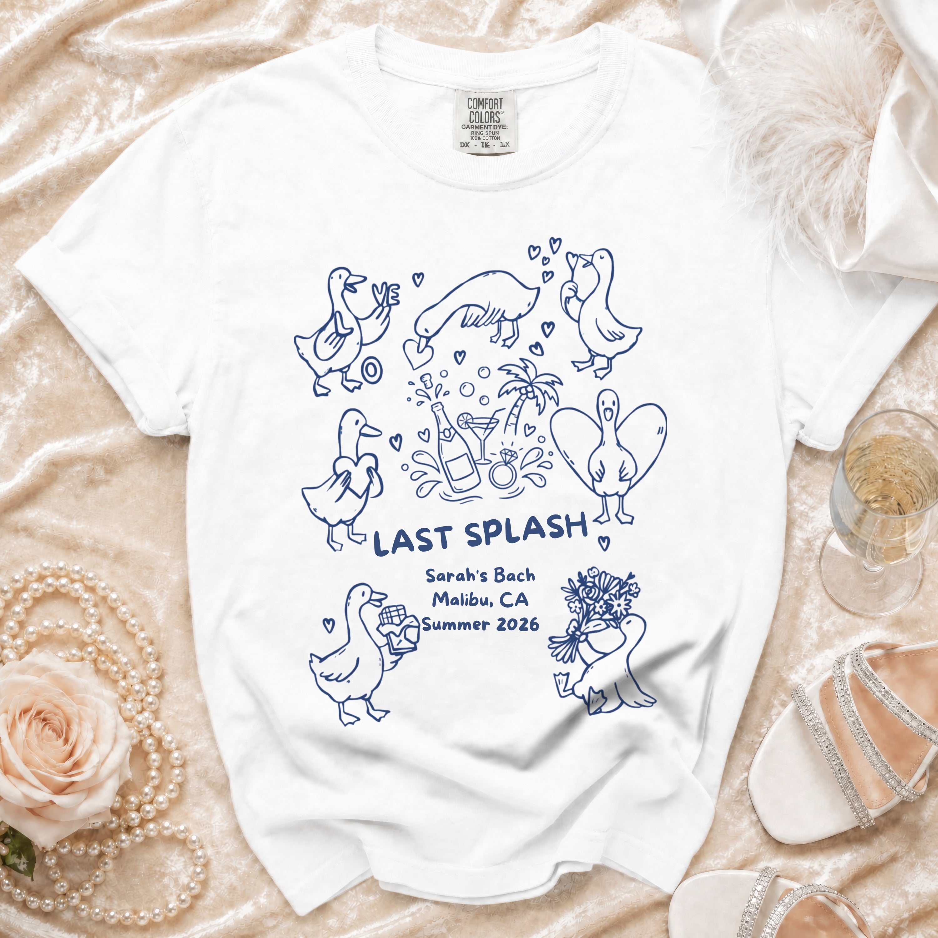 White t-shirt with blue cartoon ducks, "Last Splash", and event details.