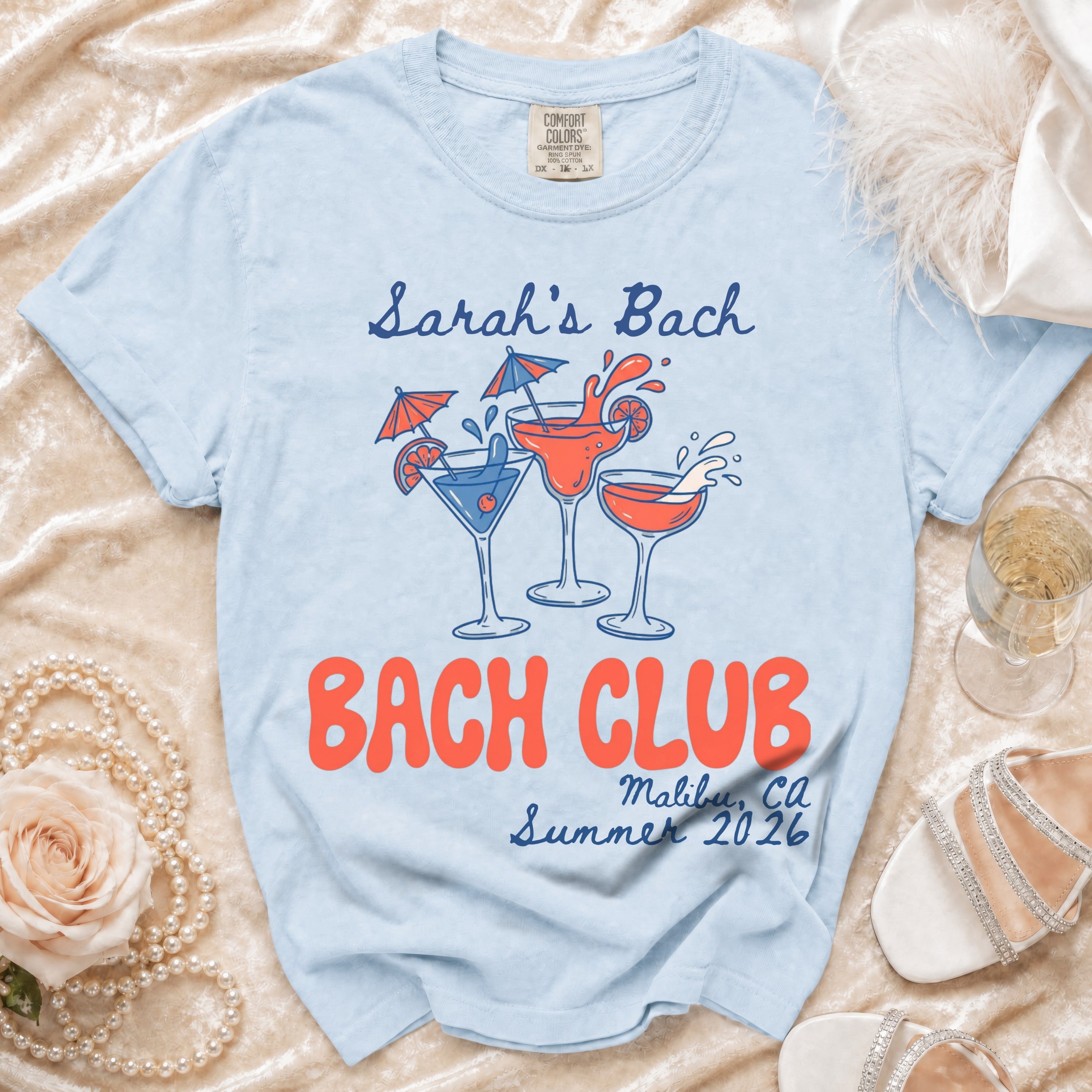 Light blue t-shirt with "Sarah's Bach," "Bach Club," and "Malibu, CA Summer 2026" text.