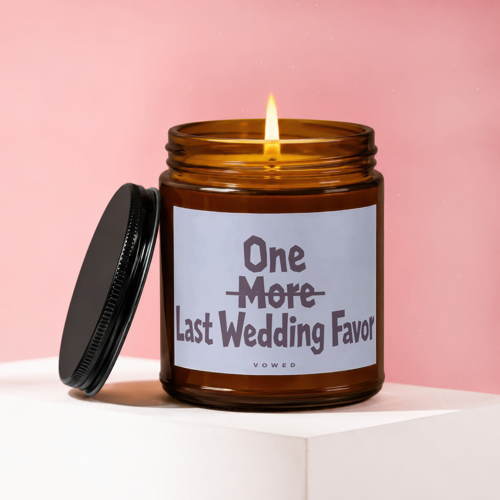 Amber glass candle with lit wick, lid off, reading "One More Last Wedding Favor".