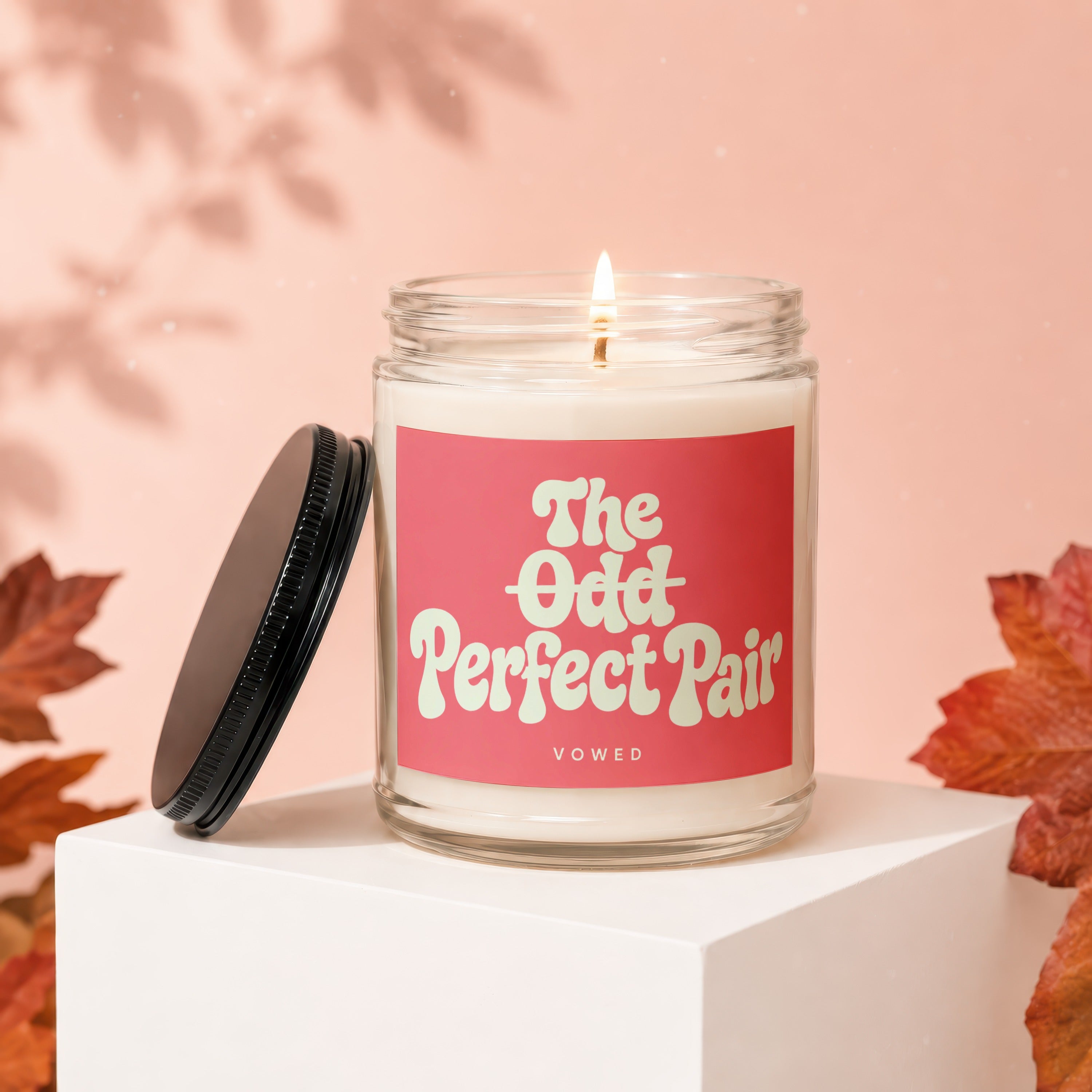 Scented candle with "The Odd Perfect Pair" text and "vowed" on a pink background.