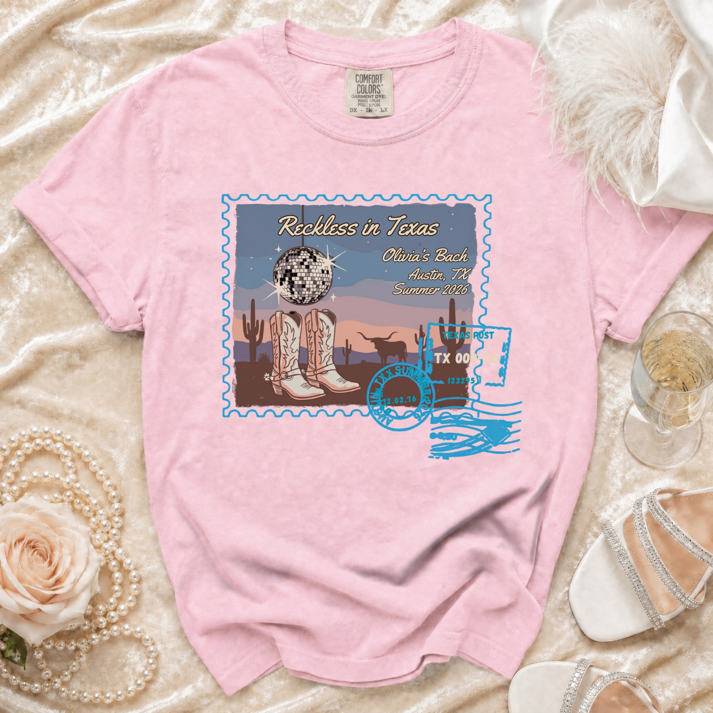 Pink t-shirt with "Reckless in Texas" graphic featuring cowboy boots and disco ball.