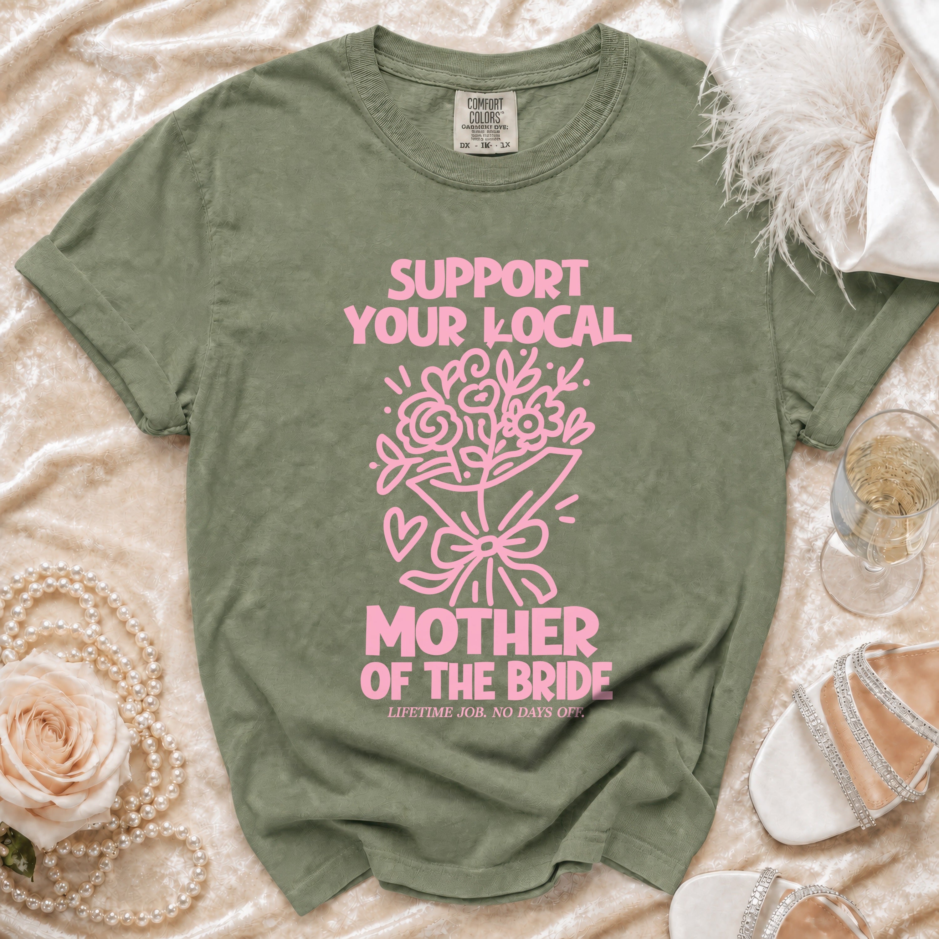 Green t-shirt with pink text "SUPPORT YOUR LOCAL MOTHER OF THE BRIDE LIFETIME JOB. NO DAYS OFF."