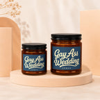 Two glass candles with dark lids labeled "Gay Ass Wedding."