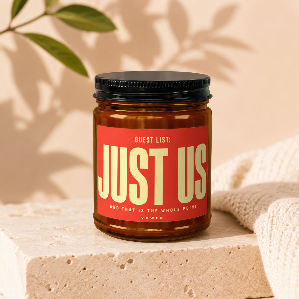 Amber jar candle with red label reading "Guest List: Just Us" and "Vowed."