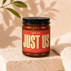 Amber jar candle with red label reading "Guest List: Just Us" and "Vowed."