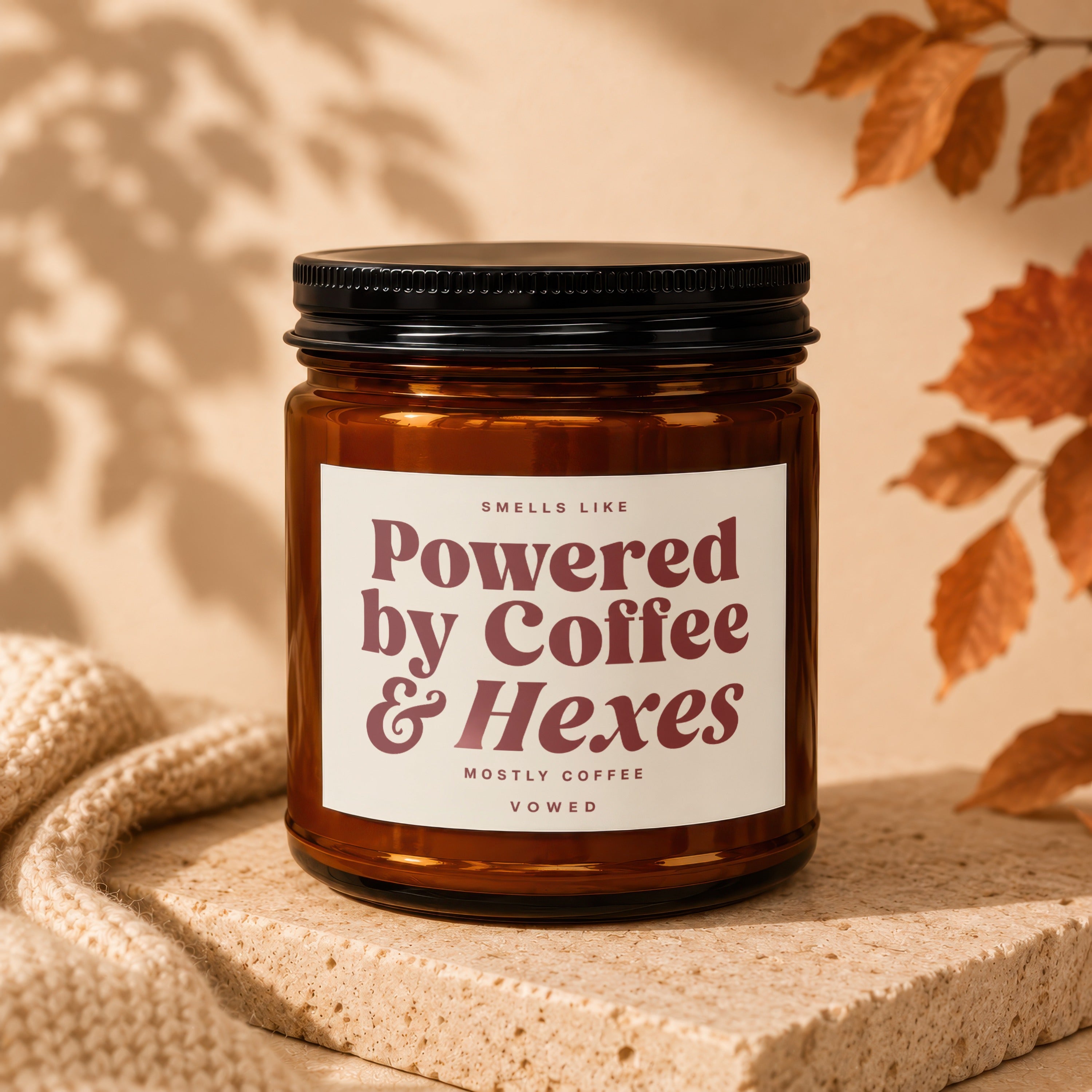 Amber candle with black lid reading "Smells Like Powered by Coffee & Hexes"