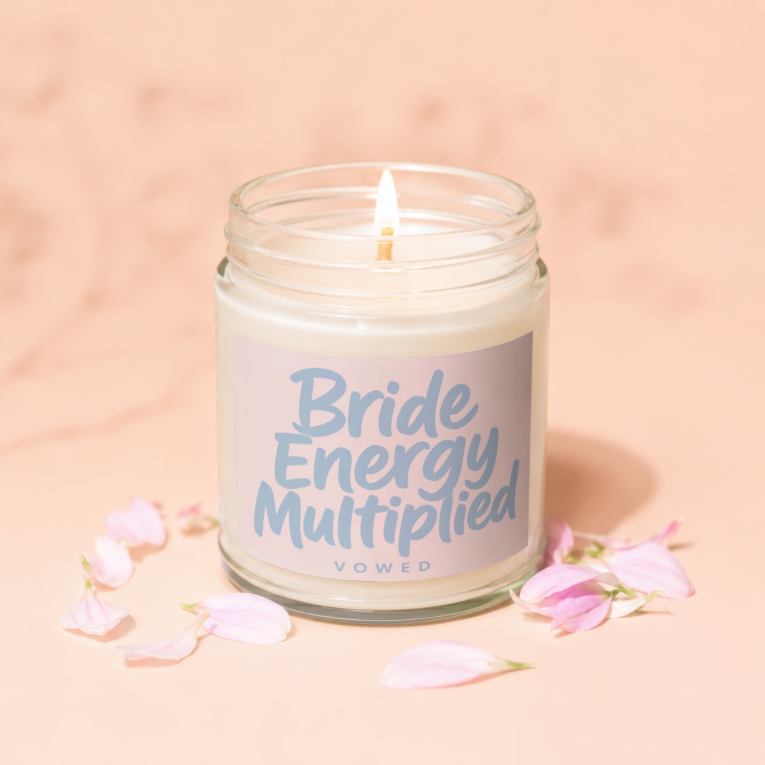 Candle with "Bride Energy Multiplied VOWED" text on label, surrounded by petals.