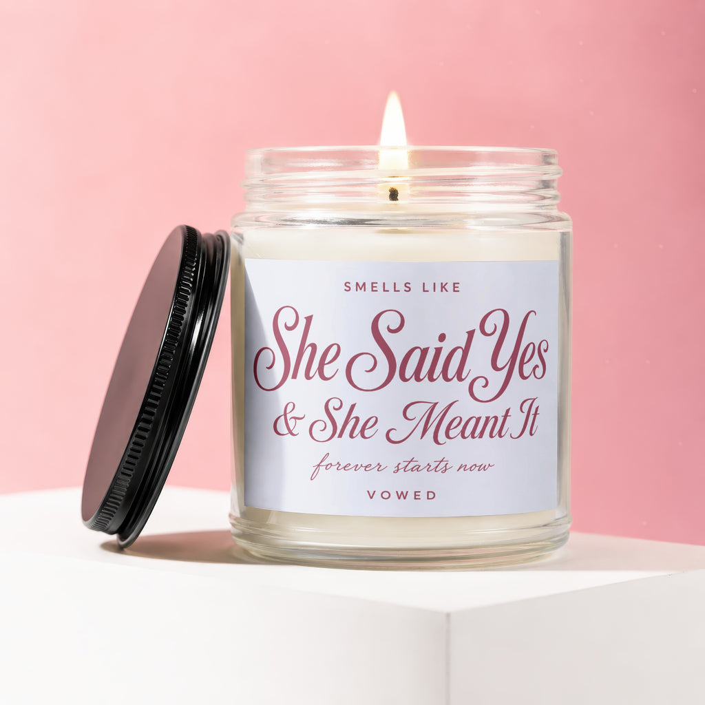 Candle in a jar with lit wick and text "She Said Yes & She Meant It".