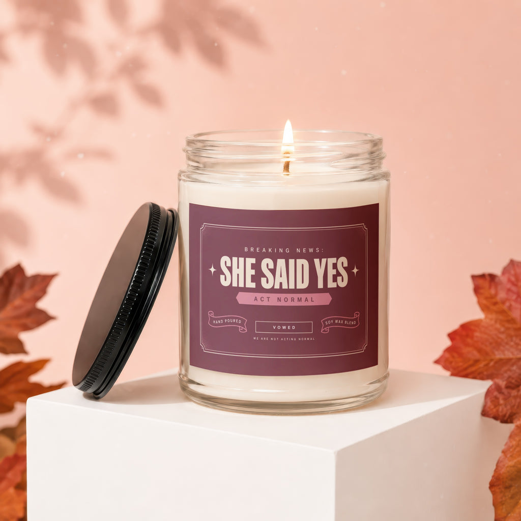 Candle with "She Said Yes" label, lit and next to its lid.