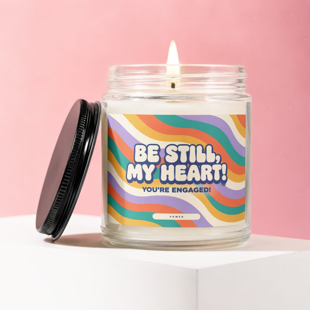 Jar candle with "BE STILL, MY HEART! YOU'RE ENGAGED! VOWED" text on retro wavy label.