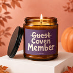 Amber glass candle with purple label reading "Guest Coven Member VOWED."
