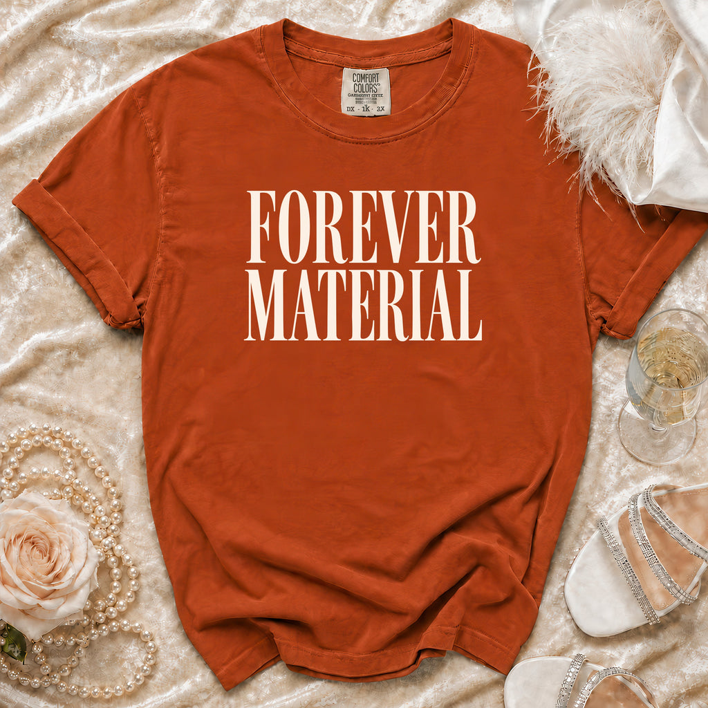Orange t-shirt with "FOREVER MATERIAL" text, styled with pearls, feather, and shoes.
