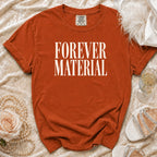 Orange t-shirt with "FOREVER MATERIAL" text, styled with pearls, feather, and shoes.