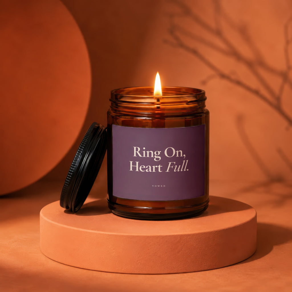 Amber jar candle with a lit flame and a purple label reading "Ring On, Heart Full."