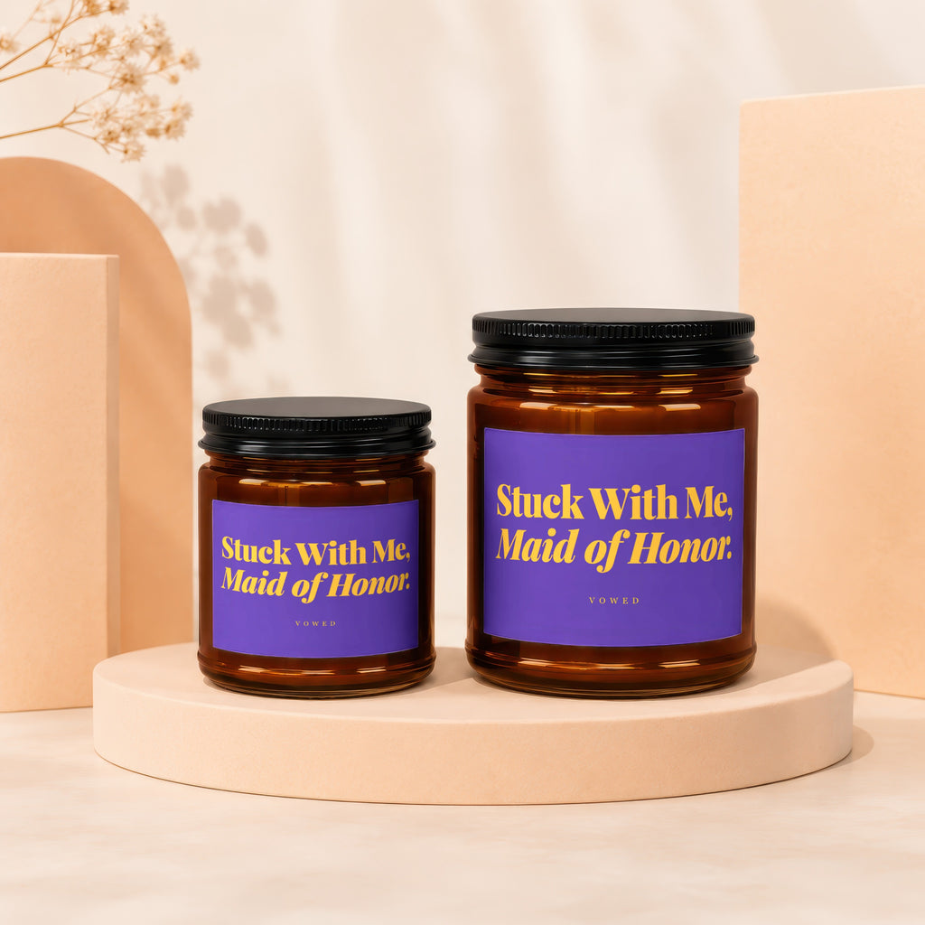 Two amber glass candles with black lids, one larger than the other, labeled "Stuck With Me, Maid of Honor."