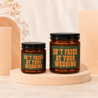 Two amber glass candles with green labels reading "Smells Like Sh*t Faced At Your Wedding".