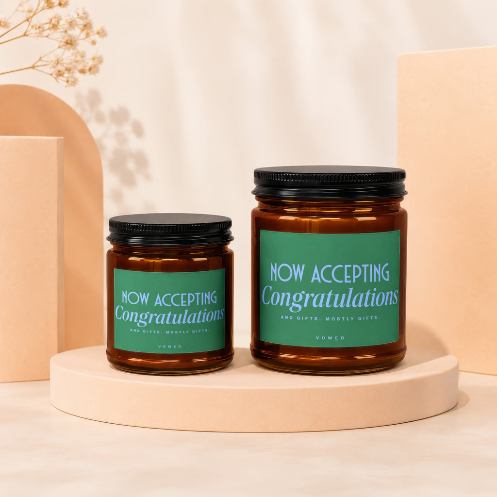 Amber glass candles with green labels reading "Now Accepting Congratulations And Gifts."