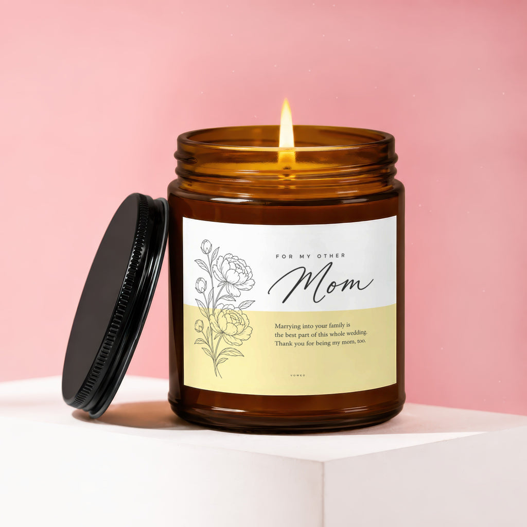 Amber jar candle with "Mom" and a floral design, lid removed.