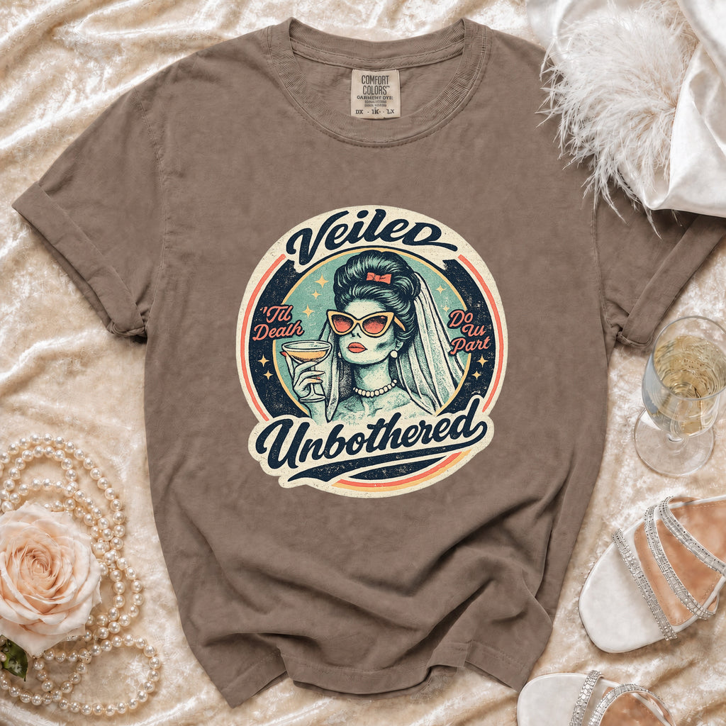 Brown t-shirt with "Veiled Unbothered" graphic of a bride holding a drink.