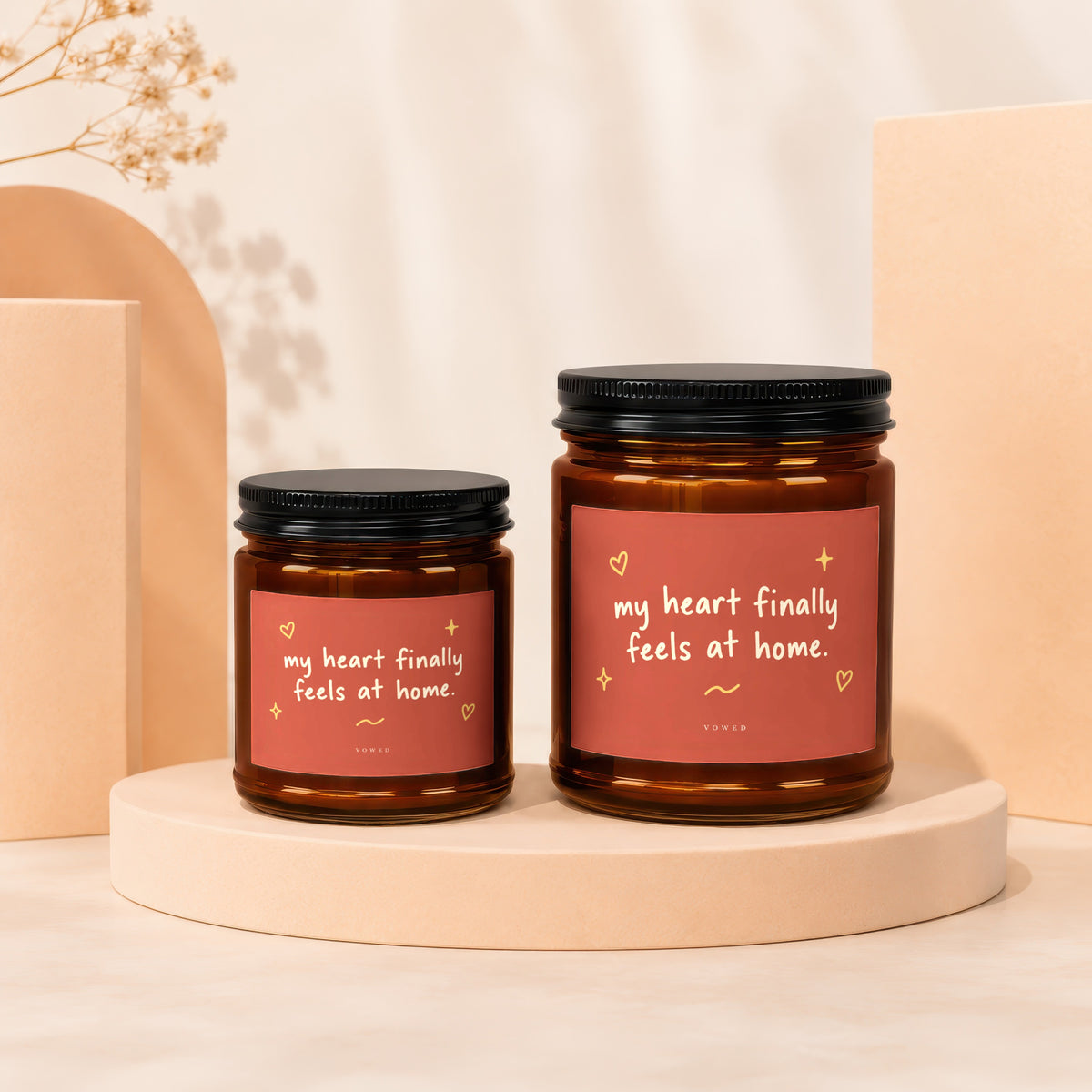 Two amber glass candles with coral labels reading "my heart finally feels at home."
