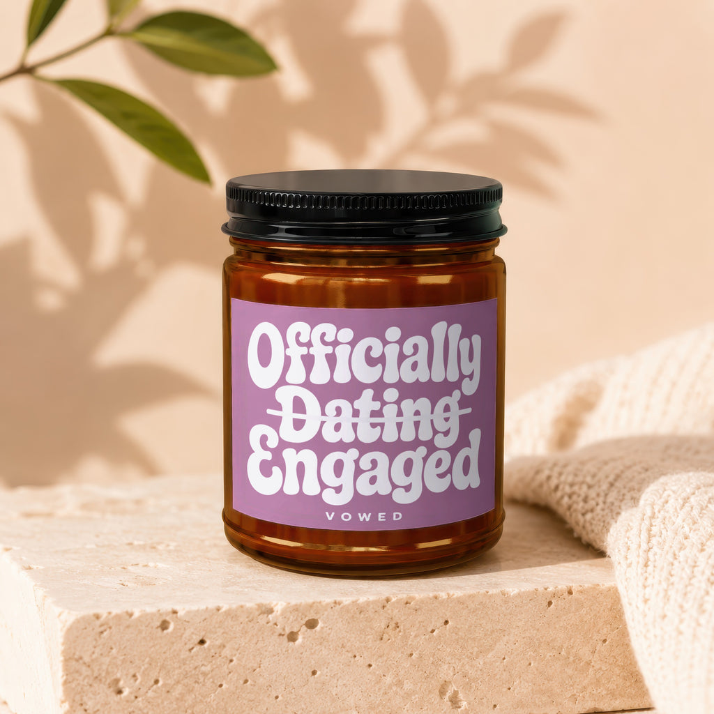 Candle with "Officially Dating Engaged" text, Vowed label, glass jar, black lid.